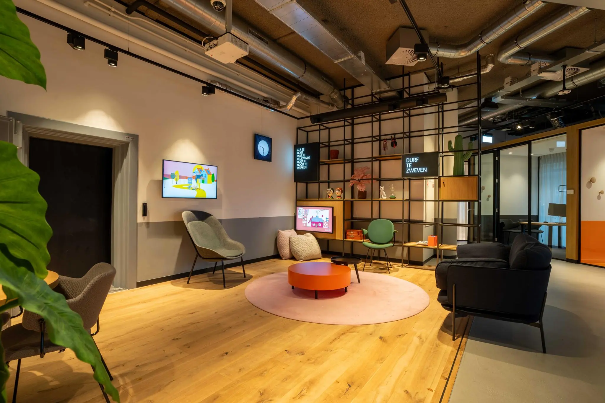 Moderne wachtruimte aan de 1e Hogeweg met kleurrijke zitmeubels, open wandkast en speelse decoratie.